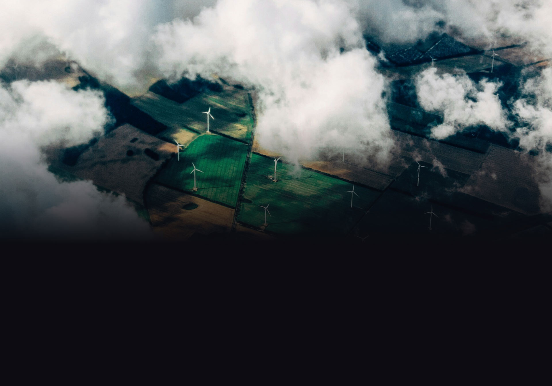 aerial view of farmland with clouds in the foreground